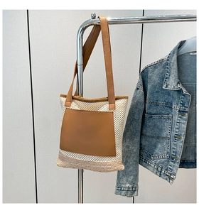 Close-up of white mesh straw tote bag with brown leather pocket and thin shoulder straps