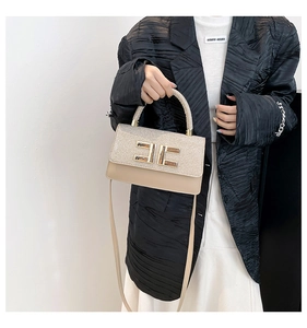 Detail view of shimmering gold sequin flap and beige leather on elegant crossbody handbag
