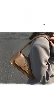 Détail du sac baguette marron brillant avec fermoir métallique en forme de nœud argenté