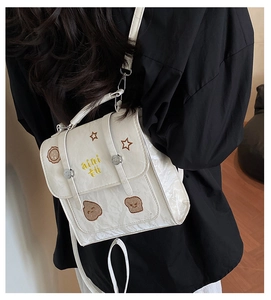 Detail of cream white textured PU backpack with yellow letter embroidery and star patterns
