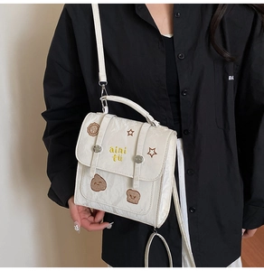 Detail of white PU leather bag featuring pleated texture and cute bear embroidery