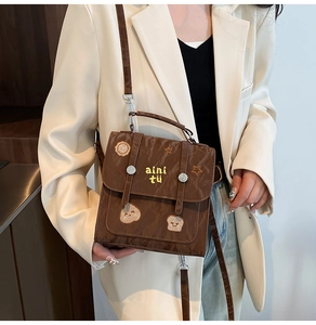 Detailed view of a brown vintage leather handbag with cartoon embroidery and aini tu logo