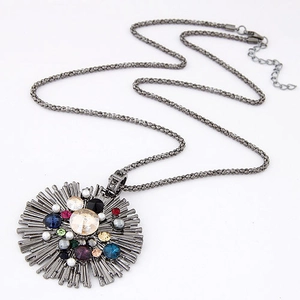 Détail d'un pendentif rond vintage avec strass colorés et perles sur une chaîne longue
