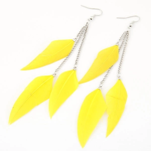 Detail of yellow feather tassel earrings with silver chains on white background