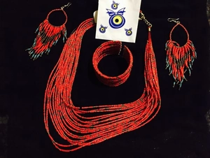 Detail of red beaded bohemian jewelry set featuring multi-layer necklace and tassel earrings