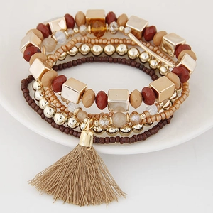 Detail of bohemian multilayer beaded bracelet with gold accents and a beige tassel charm