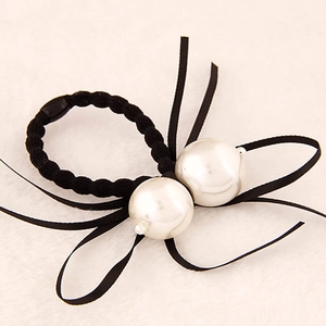 Détail d'un élastique à cheveux noir avec perles blanches et nœud en ruban délicat