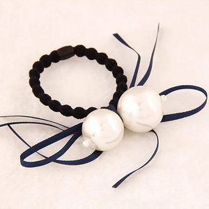Gros plan d'un élastique à cheveux noir avec perles blanches et ruban en satin bleu marine