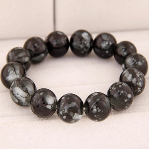 Macro detail of natural snowflake obsidian beads on elastic beaded bracelet