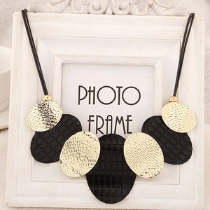 Détails des pendentifs ovales avec textures martelées dorées et mailles noires