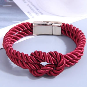 Macro shot of red braided PU leather bracelet with gold magnetic clasp and knot detail