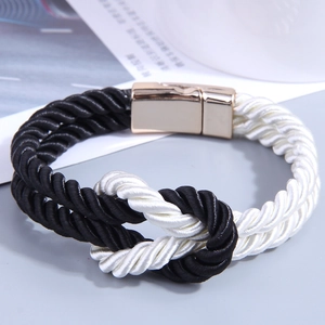 Detail of black and white woven PU leather bracelet with gold magnetic metal clasp