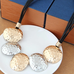 Close-up of hammered gold and silver metal charms on a multi-strand cord necklace