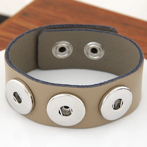 Detail eines khakifarbenen Lederarmbands mit drei silbernen Nieten und Doppel-Druckknopf