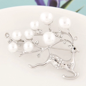 Elegant silver deer brooch with white faux pearls and clear rhinestones on white dish