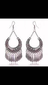 Close-up of vintage silver boho earrings featuring engraved crescents and leaf tassels