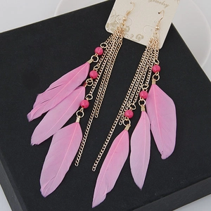 Detail of bohemian pink feather tassel earrings with delicate gold chains and bead accents