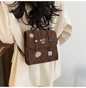 Close-up of retro brown backpack featuring cute embroidery and flip-top straps on model