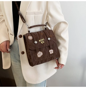 Detail of dark brown messenger bag with star embroidery and dual buckle closure