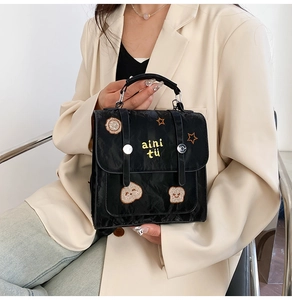 Detailed view of black textured handbag featuring playful star and bear embroidery accents