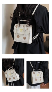 Detail of cream white mini backpack showing star embroidery and buckled closure details