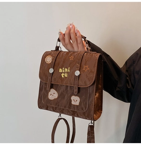 Detail of vintage brown textured leather bag with yellow embroidered star and bear patterns