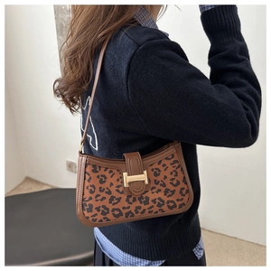 Gros plan du sac baguette léopard avec boucle dorée et bandoulière en cuir marron