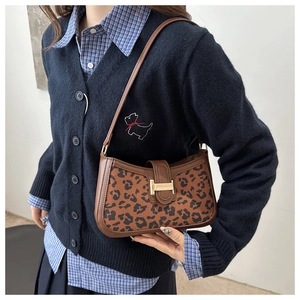 Gros plan du sac bandoulière léopard avec fermoir en métal doré et finitions en cuir
