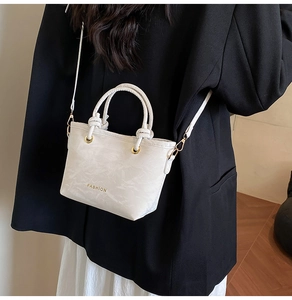 Close-up of white pleated mini bucket bag with gold hardware and fashion lettering