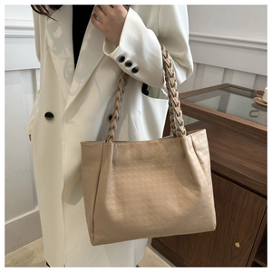 Détail d'un sac cabas beige avec surface texturée et poignée tressée épaisse unique