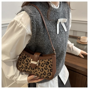 Détail du sac à bandoulière léopard avec fermoir doré porté par un mannequin en tenue