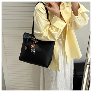 Détail du grand sac cabas en cuir noir avec foulard en soie porté par un mannequin