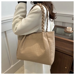 Dettaglio borsa tote beige con rilievo pied-de-poule e manici a treccia eleganti
