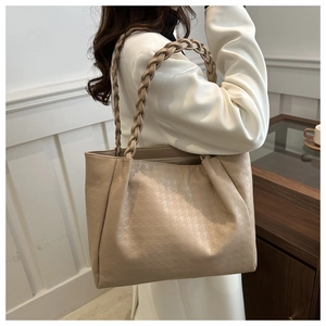 Dettaglio borsa tote beige con manici intrecciati e trama a quadretti pied-de-poule