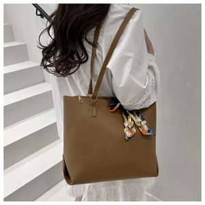 Détail d'un sac cabas en cuir marron avec foulard décoratif et fermeture éclair dorée