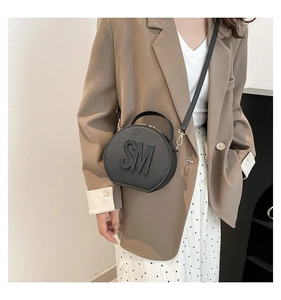 Fashionable black round handbag with SM embossed logo styled with a chic brown blazer outfit