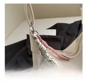 Detail of silver tennis racket pendant and braided charms on a white tote bag
