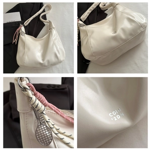Detail of cream hobo bag featuring tennis racket charm and woven rope decoration