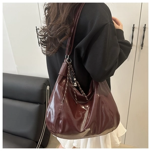 Detail of burgundy patent leather tote with woven strap ornament and glossy finish