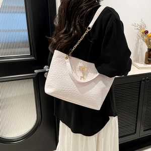 White woven embossed tote bag with gold chain strap and deer pendant on model