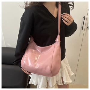 Detail of pink patent leather hobo bag with white branding text shown on model