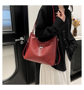 Detail of red woven texture hobo bag with a silver butterfly buckle and shoulder strap