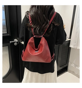 Detail view of the red woven leather backpack featuring a silver metal bow accent