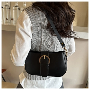 Détail du sac sous le bras en cuir noir avec boucle dorée vintage et bandoulière fine