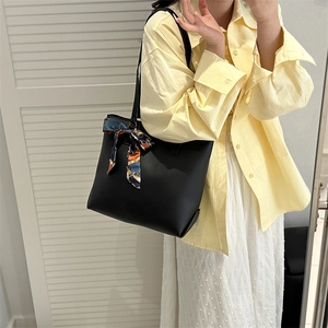 Sac cabas noir en cuir avec détail écharpe en soie bleue porté par un mannequin