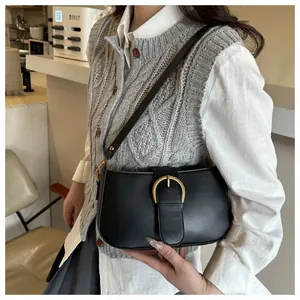 Détail d'un sac demi-lune en cuir noir avec une boucle dorée en fer à cheval et bandoulière