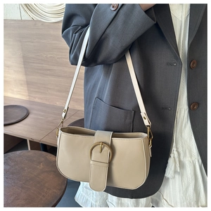 Gros plan d'un sac porté épaule beige en cuir avec boucle vintage et fine bandoulière