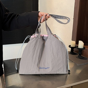 Minimalist grey nylon drawstring tote bag with contrast pink lining and embroidery