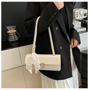 Détail du sac baguette blanc crème avec boucle argentée et foulard en soie décoratif