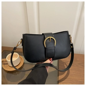 Détail d'un sac sous le bras noir chic avec une boucle métallique circulaire dorée vintage